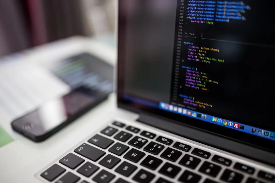 A stylesheet open in a dark editor beside a laptop keyboard